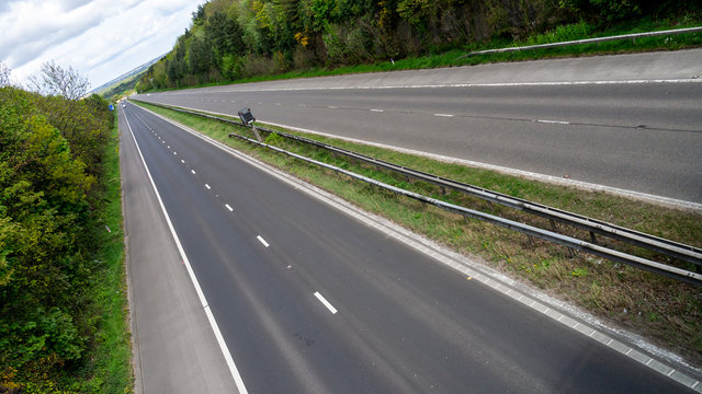 Dynamic view of a quiet dual carriageway with cars off to the distance and vivid green trees on either side.  This is the A194 in the North East of England.