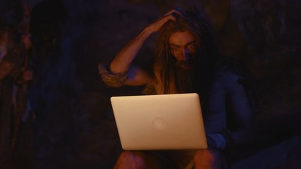 Prehistoric cro-magnon IT technologist using laptop computer at bonfire. Portrait of ancient...