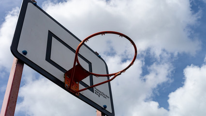 Outdoor Basketball hoop with white wooden backboard, black indication strips and faded red metal...