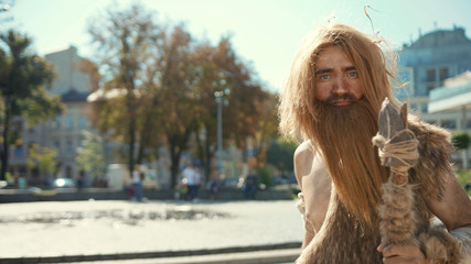 Ancient discoverer wildman in animal fur exploring future city architecture modern civilization...