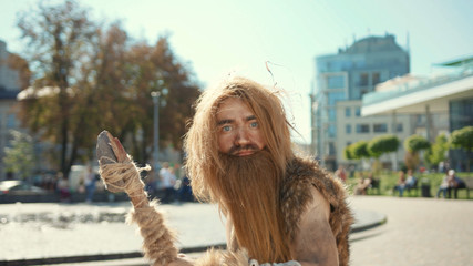 Ancient discoverer wildman in animal fur exploring future city architecture modern civilization...