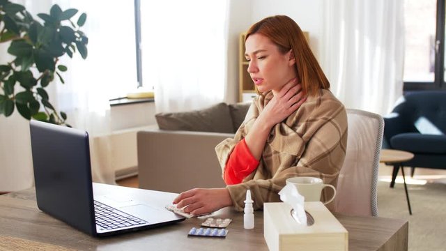 medicine, healthcare and technology concept - sick young woman having video call or online consultation on laptop computer at home showing drugs and sneezing