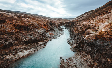 Amazing Nature landscape of Iceland. Impressively beautiful Studlagil canyon with basalt columns and colorful sky during sunset. Tipical Iceland scenery. Iconic location for photographers and bloggers