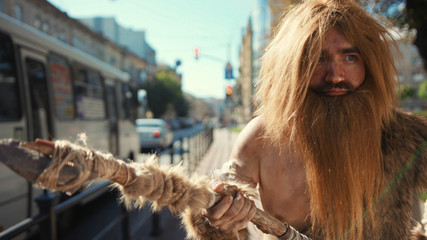 Primitive wild people of hunter-gatherers walking in modern city attacking cars like hunting...
