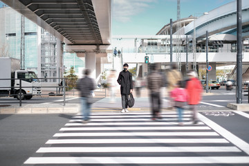 Young man wear black face mask and waiting to crossing road under the concrete bridge near electric train station
