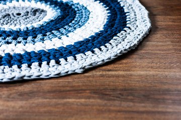 handmade round wicker rug on a wooden floor, cozy home interior decor in blue, gray and white...