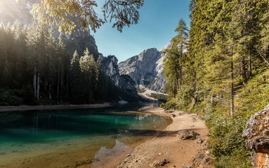 Sunny Autumn landscape. Incredible view on Famous Braies lake under sunlight. Amazing Lago di Braies during sunrise. Wonderful mountain lake in Dolomites Alps. Italy. Iconic location for photographers