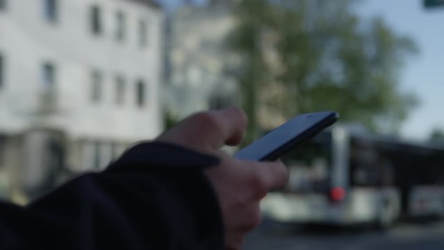 Waiting with smartphone the bus stop with bus in background