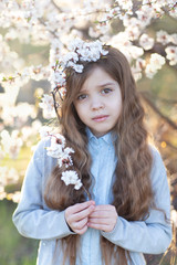 Fototapeta premium Portrait of a little girl next to a flowering tree