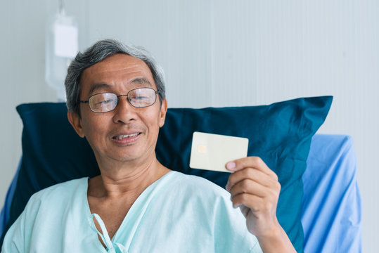 Asian Patient Elderly Man Showing Credit Card On Hospital Bed In Hospital. Payment Health Insurance Medical Treatment Concept