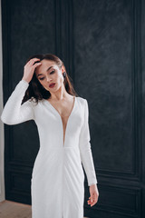 a beautiful bride in a white glittering wedding dress with brown hair poses in a photo Studio