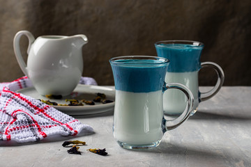 2 glasses of blue Dalgona Matcha Blue Latte, cream drink from pea butterflies on a light gray background. Horizontal orientation