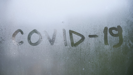 Worldwide coronavirus quarantine and insulation. The inscription covid 19 on the foggy rainy window.
