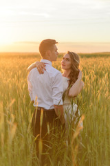 Bride and groom in a wheat field. A couple is hugging during sunset.