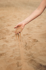Woman holding a sand in the hand  on the desert. Sand falling from the female hand on the beach at evening.