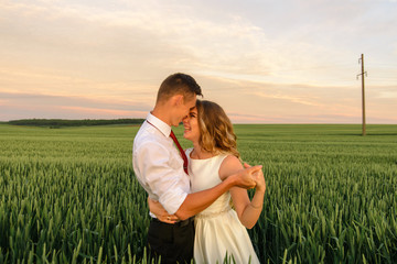 Bride and groom in a wheat field. A couple is hugging during sunset.