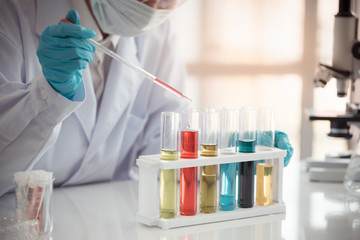 Scientist hold pipette adding fluid to test tubes or glassware with copy space using as background...