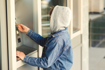 Boy takes money in cash dispenser for alien card. Boy takes cash at ATM machine.