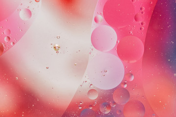 Fond de bulles abstraites - huile dans l'eau sur un arrière-plan flou dans des tons rose rouge