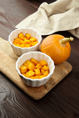 Baked pumpkin in white ceramic bowl on wooden background
