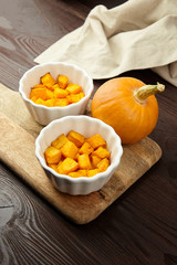 Baked pumpkin in white ceramic bowl on wooden background