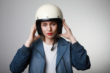 Close-up portrait of attractive biker woman wearing white helmet and shows safety conditions. Space for text.