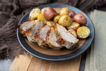 Roasted pork with spices and Parmesan roasted baby potatoes. Close up on a plate. 