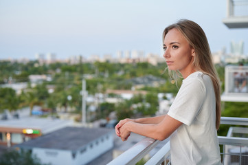 Fototapeta na wymiar Single female standing outside on residential balcony sunset isolation