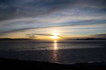 Fototapeta premium Ice lake under sunset, dark mountains in the distance