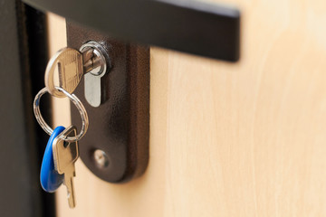 Close-up of metal keys and key chain in the door lock of the house and office. Security concept against hacking of apartments and apartments