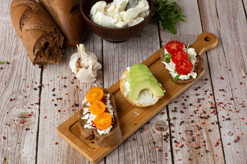 Bruschettas with vegetables. Start dishes with cherry tomatoes, avocado, cream cheese. Delicious snacks with chorizo and baked tomatoes. Food composition, tasty italian meal.