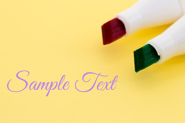 Colored markers - red and green, isolated on the yellow background with place for text.