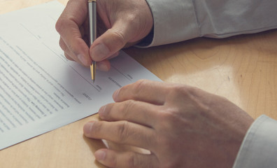 Naklejka premium A person signing a document. Hand holding a pen and signing a contract. 
