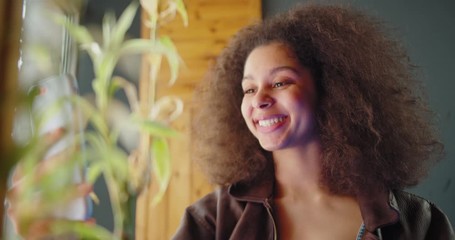 Positive african american young woman laughing while video chat conference on smartphone device and chatting online in social networks using wireless internet at home apartment - Powered by Adobe