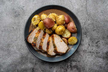 Roasted pork with spices and Parmesan roasted baby potatoes. Close up on a plate. 
