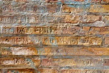Brick wall with carved in names. Rich texture for background, wallpaper etc.  Pattern frontal...