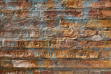 Brick wall with carved in names. Rich texture for background, wallpaper etc.  Pattern frontal...