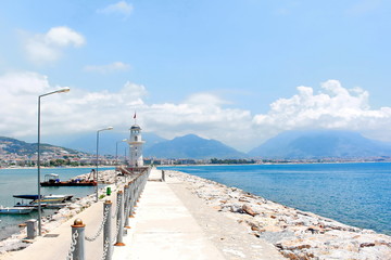 Obraz premium white beautiful lighthouse on a sea pier on a blue sky background on a sunny day