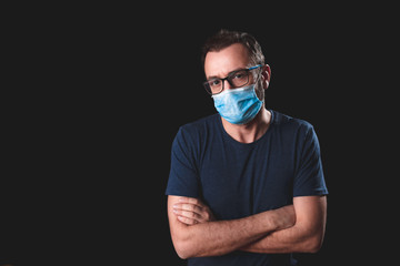 Adult person with protective face mask posing on a black background - social issues with virus and...