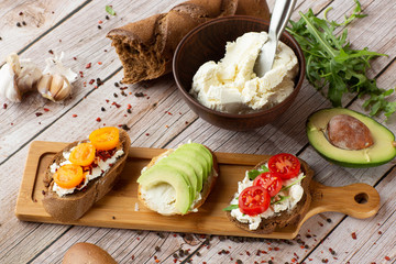 Bruschettas with vegetables. Start dishes with cherry tomatoes, avocado, cream cheese. Delicious snacks with chorizo and baked tomatoes. Food composition, tasty italian meal.