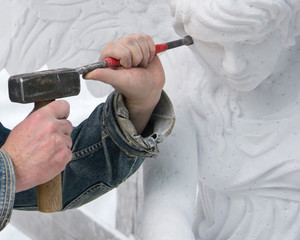 Sculptor at work. Stone carving. Hands with a hammer.