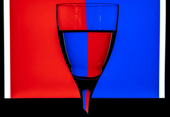 Glass of water against a two-color background. Water in refracting light. Still life