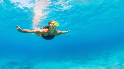 Happy family - active young woman in snorkeling mask dive, swim underwater to see tropical fishes...