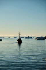 Telephoto shot of boat among the icebergs in Disko bay Ilulissat