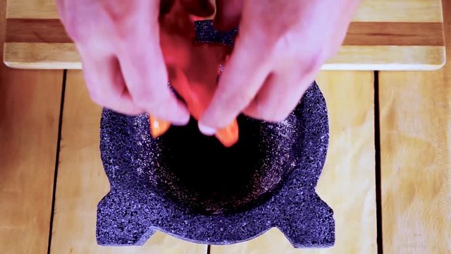 Preparing red hot chilli peppers in a morter for a hot sauce
