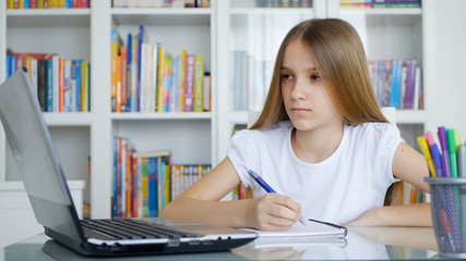 Fototapeta na wymiar Kid Using Laptop Studying in Video Conferencing, Child Learning, Writing in Library, Schoolgirl Chatting with Teacher from Home in Coronavirus Pandemic Crisis, Children Homeschooling, Online Education