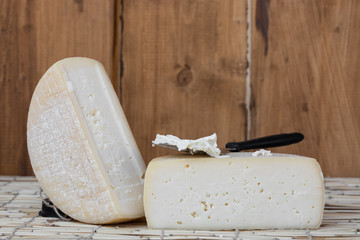 Fototapeta na wymiar Slice of hard cheese, goat's milk cutting with cheese knife . Typical soft texture and whitish color. Farm homemade cheese. The concept of nutrition and healthy lifestyle.