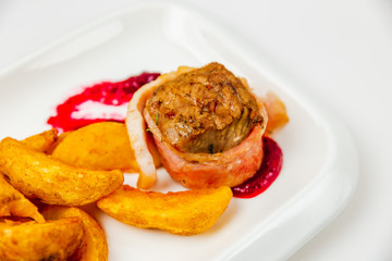 Fillet mignon rolled in bacon and baked in oven with berry sauce. Potato for garnish. Close-up photo