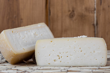 Two big organic cheese heads in the wooden background in the farm kitchen. Food concept. Farm cheese. Cheese Fair. Sliced round white homemade cheese - traditional milk creamy dairy product.