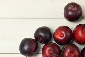 Fresh juicy plum fruit close-up on a white wooden background. Fresh Farm Organic Plum Harvest
